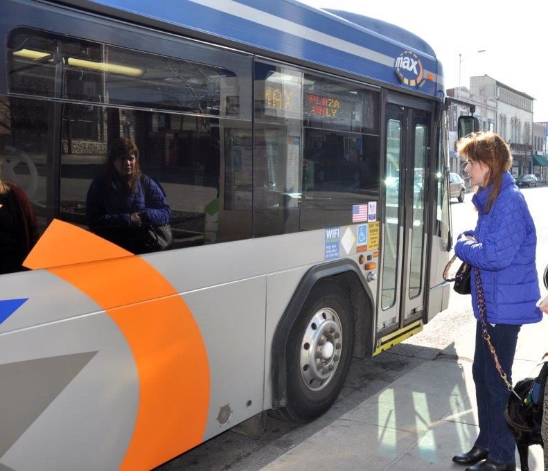 Pictured: Erika, holding her bag and her guide dog's leash, waits to board a Kansas City Metro Max bus.
